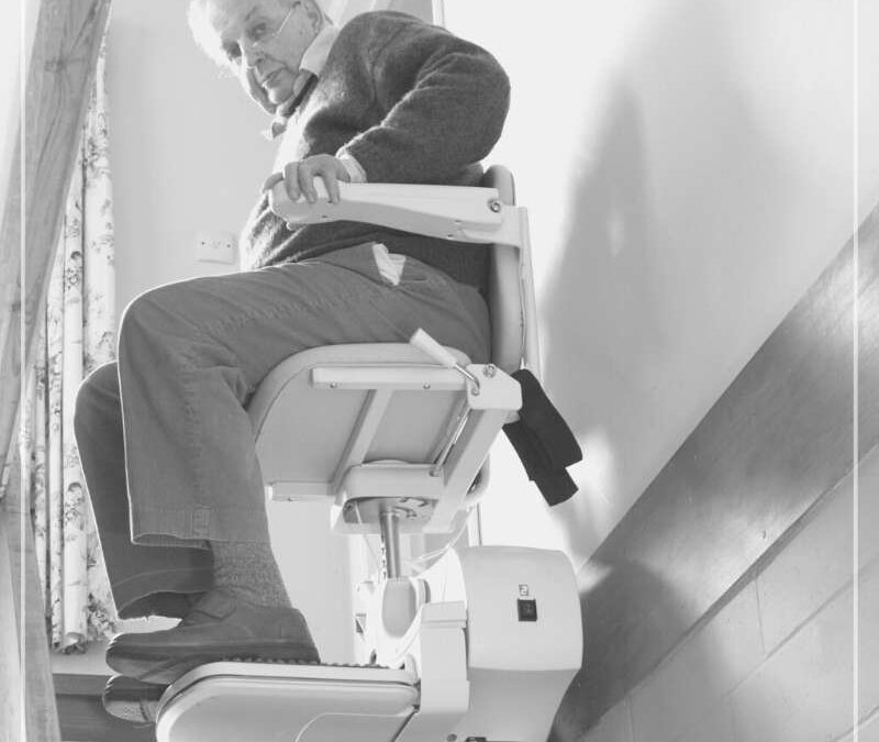 Señor mayor subiendo una escalera montado en una silla salva escaleras