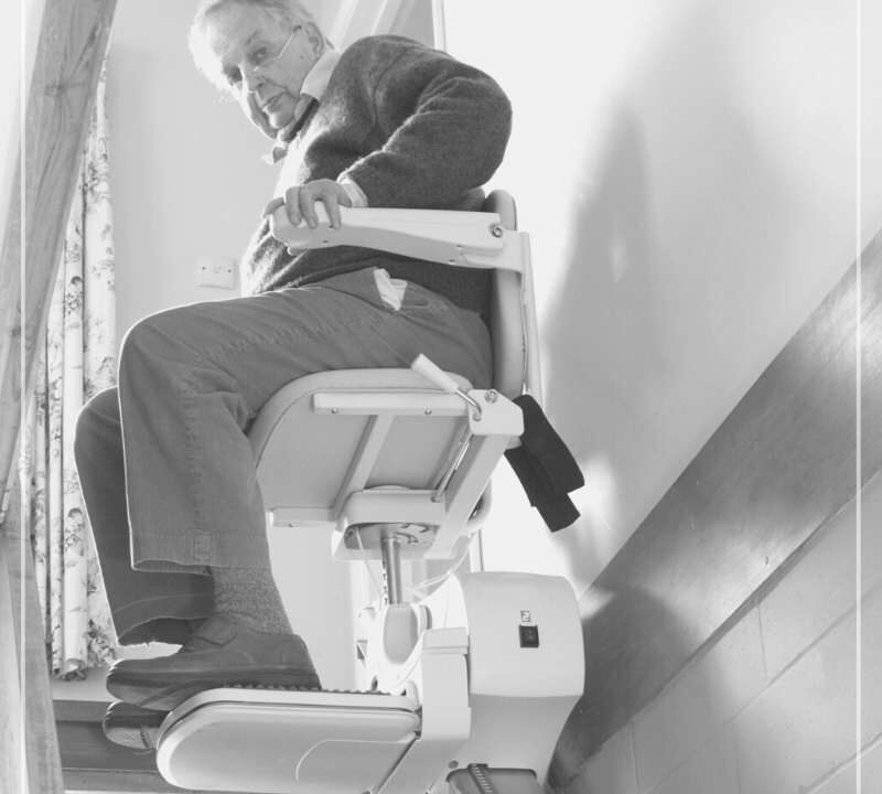 Señor mayor subiendo una escalera montado en una silla salva escaleras